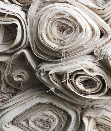 Many rolls of white fabric stacked toegther